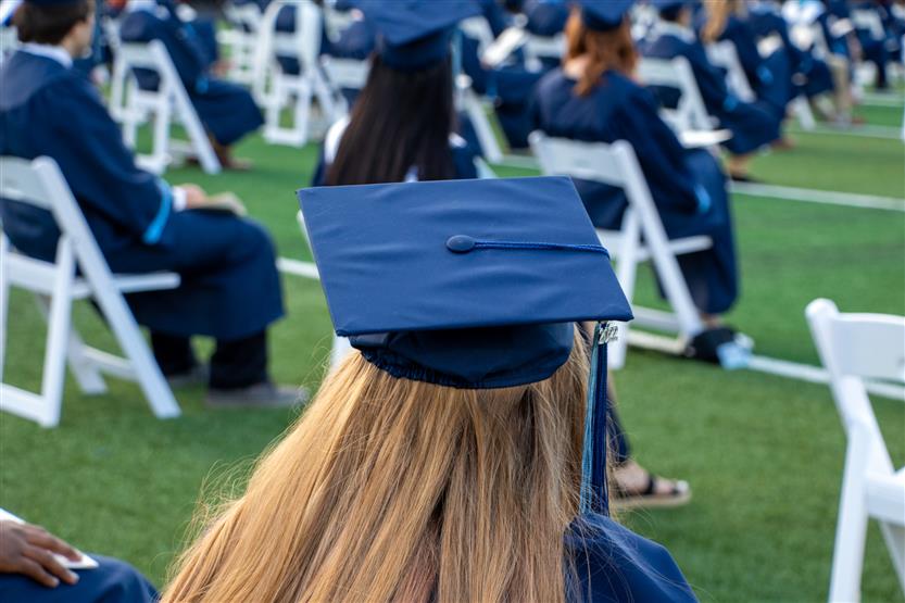 Students graduate outside on a football field